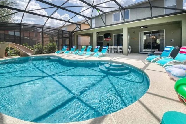 The Minion Mansion, Private pool with slide and covered lanai, lounge chairs, outdoor smart tv and outdoor dining with plenty of comfortable seating, and ping pong table.