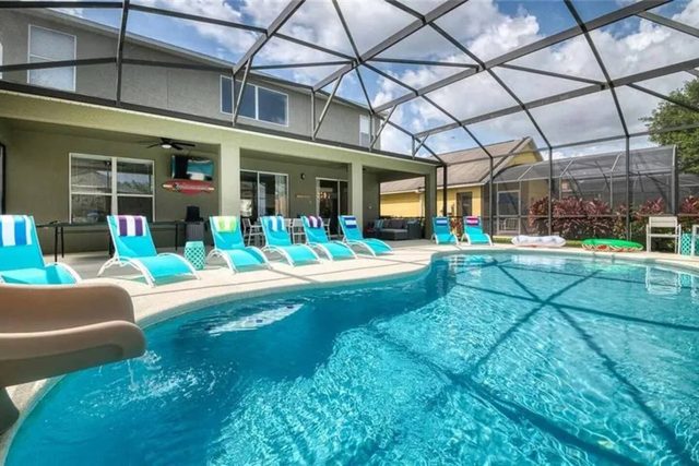 The Minion Mansion, Private pool with slide and covered lanai, lounge chairs, outdoor smart tv and outdoor dining with plenty of comfortable seating, and ping pong table.